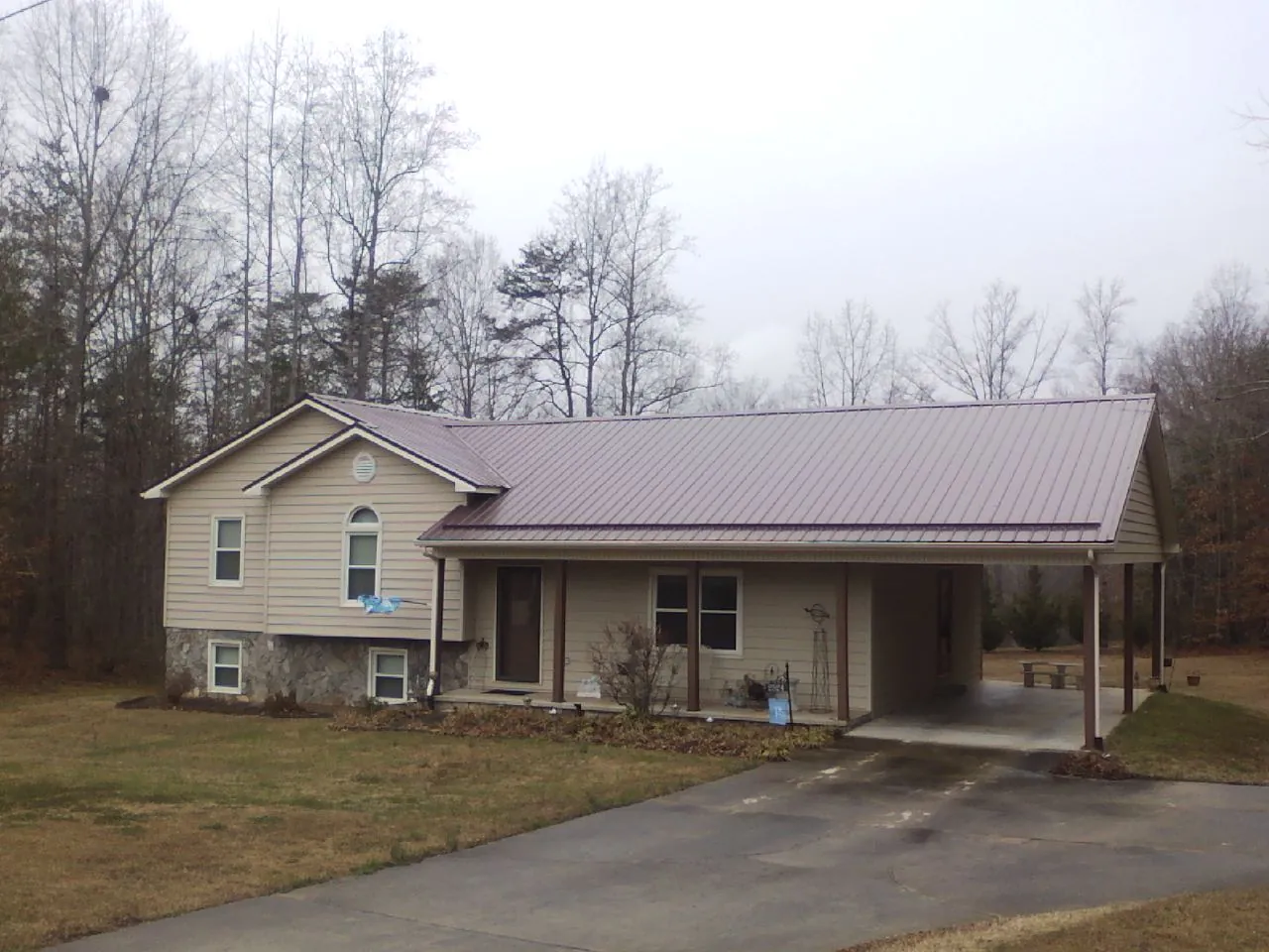Burgundy metal roof on a tan split level home with an attached carport in Hacksneck