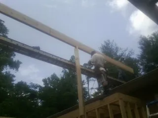 Carpenter setting a ridge beam over a new addition frame — Ice Dam Removal by Roofing Brothers in Hacksneck