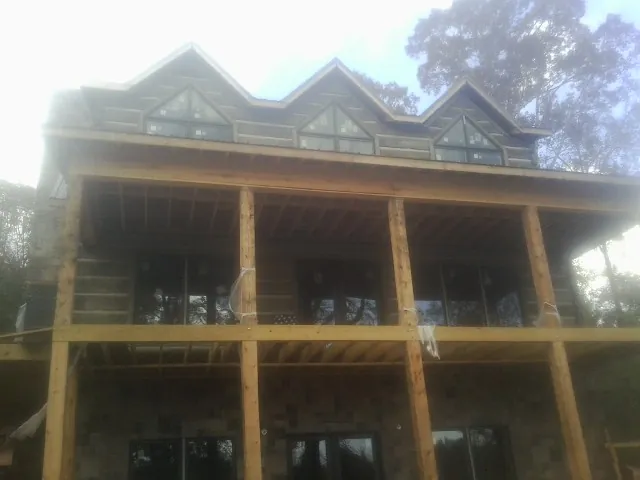 Dormers and porch framing on a large log home under construction — Roof Coating work by our crew in Hacksneck