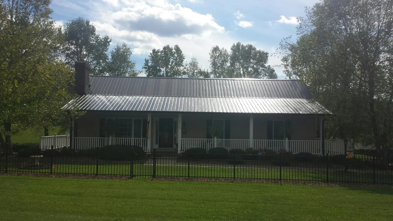 Gray metal roof on a brick ranch with a full width front porch — Gutter Guard Installation work by our crew in Hacksneck