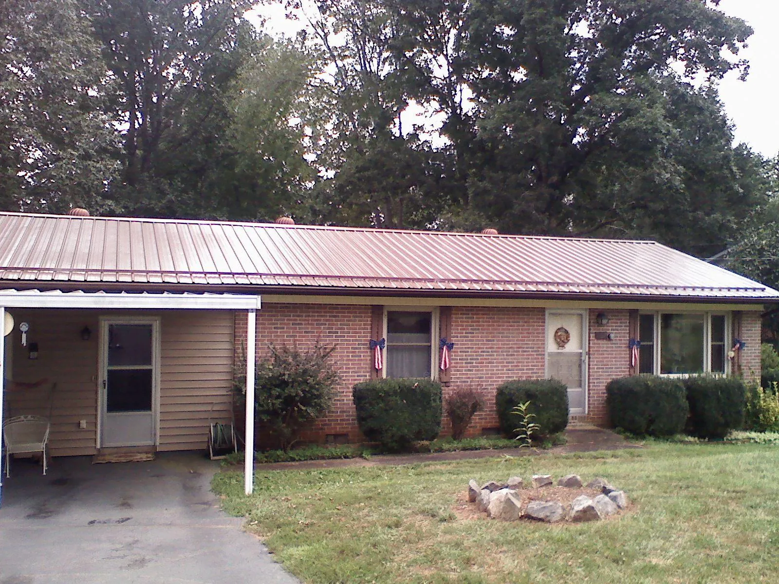 Bronze metal roof and carport on a brick ranch home — Roof Repair work by our crew in Hacksneck