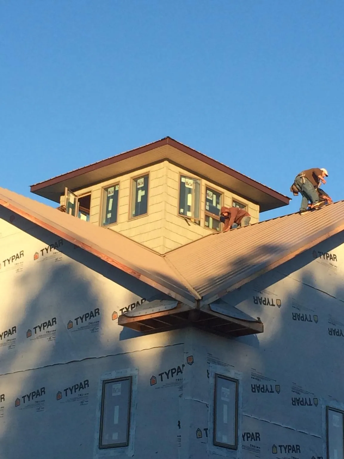 Roofers working around a rooftop cupola on a new metal roof at sunset — Roof Waterproofing in Hacksneck by Roofing Brothers